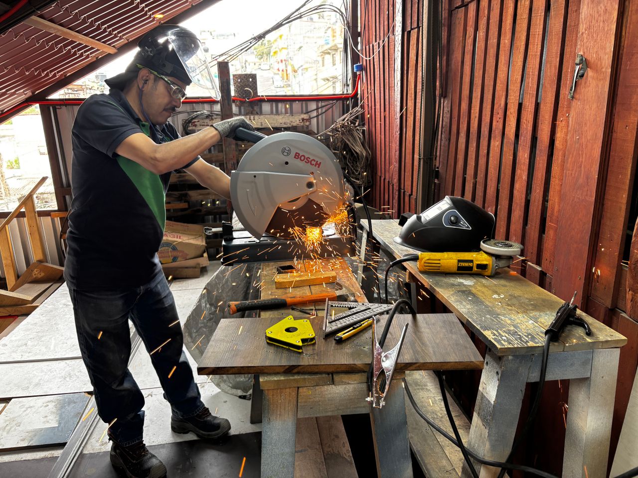 who-we-are A man cuts metal with a saw in a workshop, creating vibrant sparks.